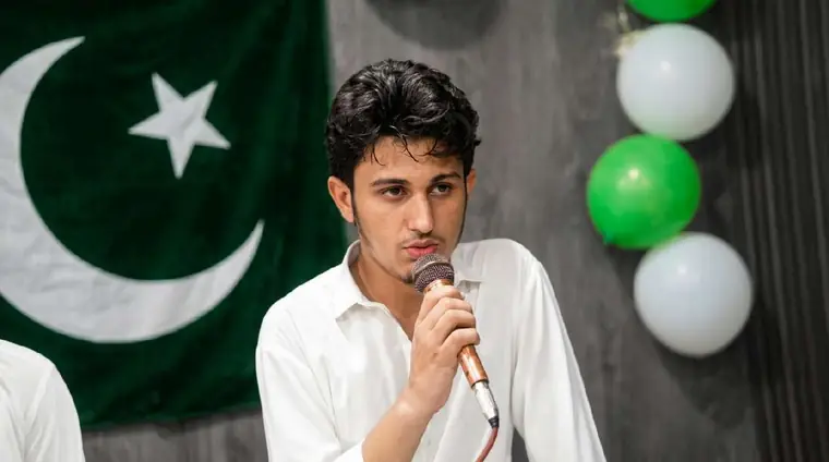 Student holding a microphone while presenting at a KISI campus celebration with balloons