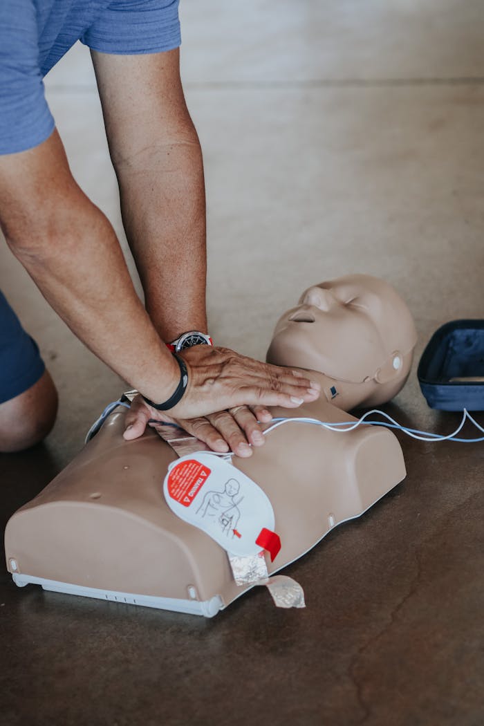 Hands demonstrating CPR technique on a training mannequin with AED.